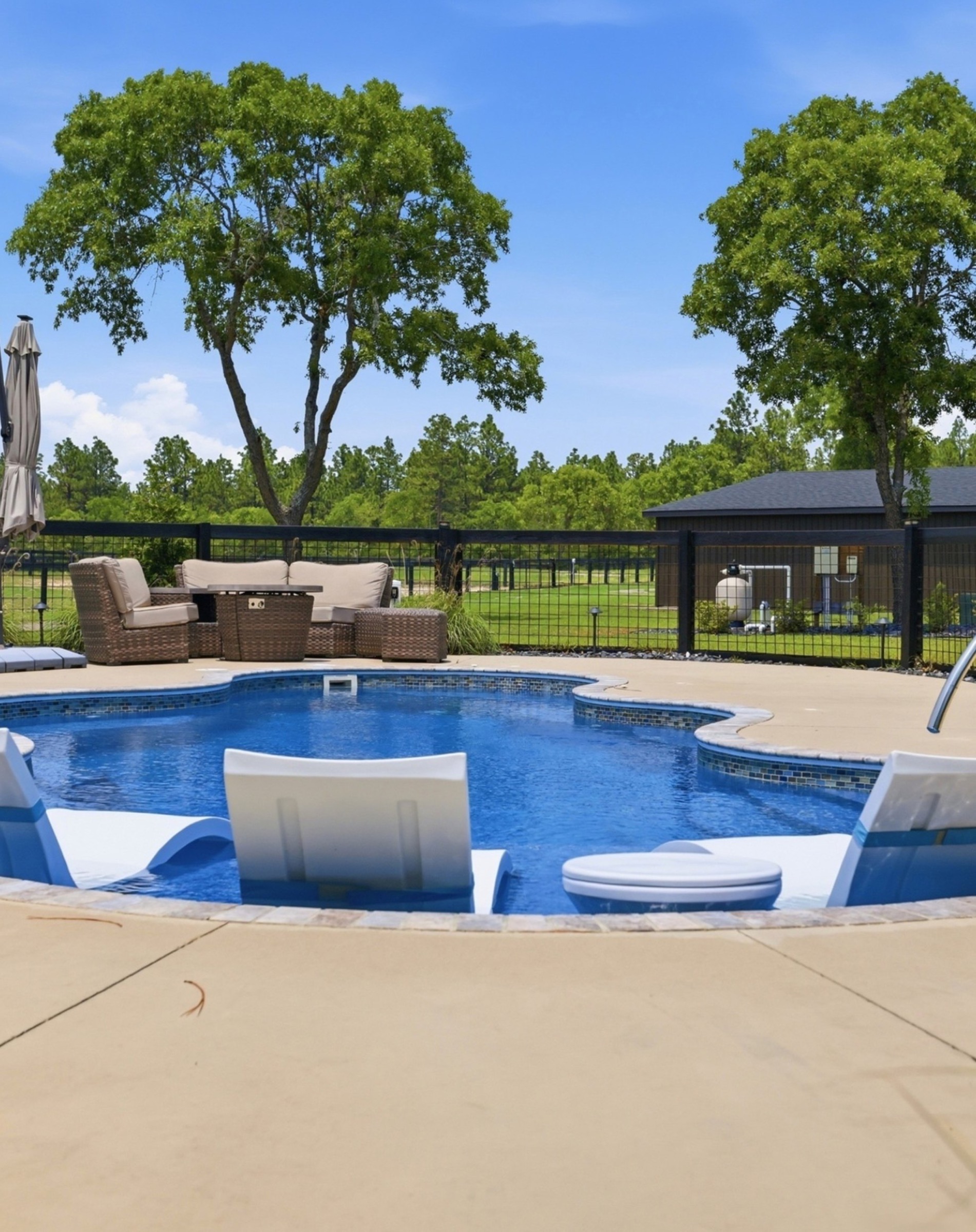 Saltwater pool behind the home at 8520 Stock Horse Trail, black fence and pastures beyond.