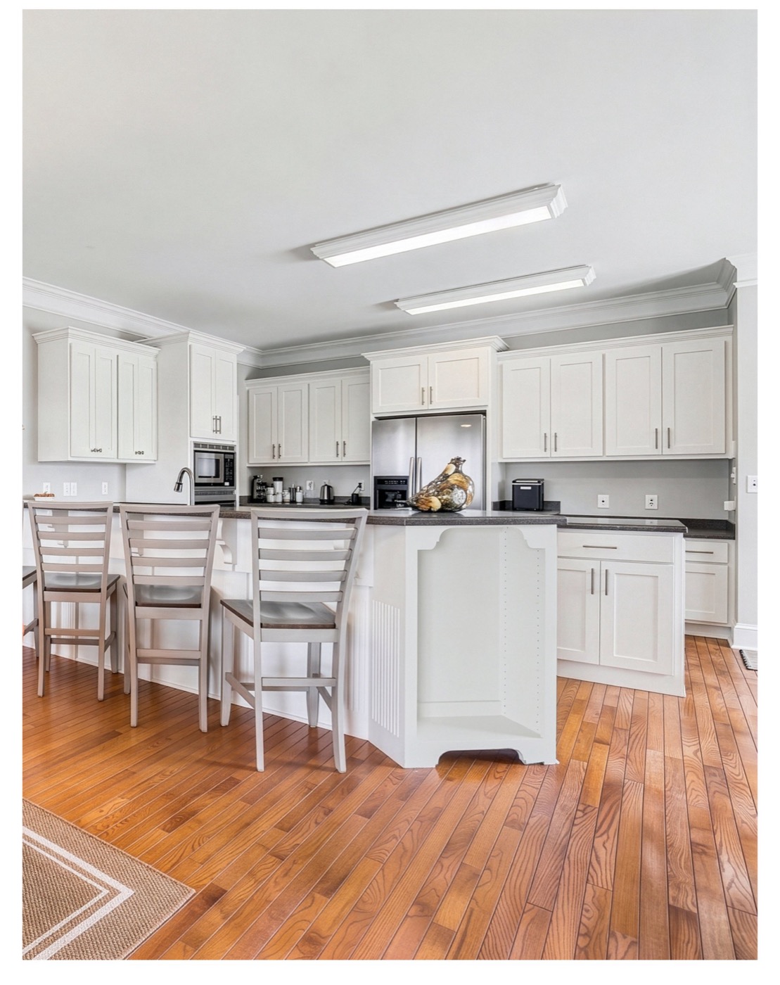 Kitchen at 8520 Stock Horse Trail with white cabinetry, a center island, and white oak floors.